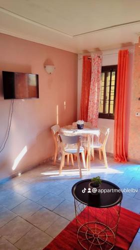 ein Wohnzimmer mit einem Tisch und Stühlen sowie einem TV in der Unterkunft Appartements Benedicta in Libreville