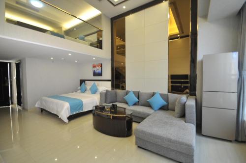 WAIFIDEN Duplex Hotel Apartment Zhongyong Jinyu Branch في قوانغتشو: غرفه فندقيه بسرير واريكه