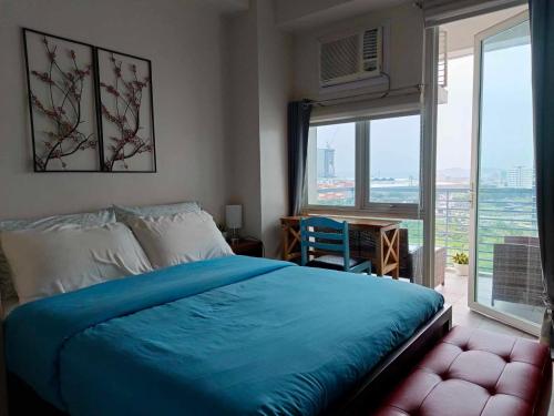 een slaapkamer met een blauw bed en een groot raam bij Executive Studio at One Madison Place Iloilo City in Iloilo City