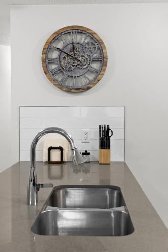 a clock on the wall above a kitchen sink at GlobalStay Cranbrook Townhome Suites in Calgary