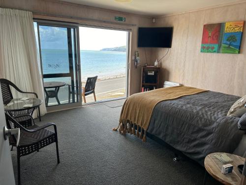 a bedroom with a bed and a view of the ocean at Te Mata Bay Seaviews in Tapu