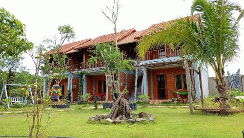 a house with a palm tree in front of it at Sunny Eco Lodge in Cat Tien