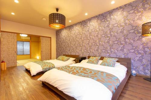 a bedroom with two beds and a purple wall at Kanmuritei Guest House UP to 7 pax, 冠邸l和モダン最大7名まで宿泊可能 in Kyoto