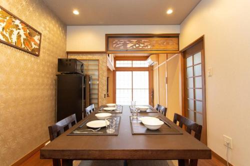 a dining room with a long table and chairs at Kanmuritei Guest House UP to 7 pax, 冠邸l和モダン最大7名まで宿泊可能 in Kyoto