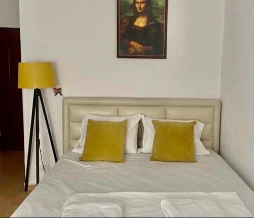 a bed with white sheets and yellow pillows in a bedroom at Livi beachfront Apartment in Durrës