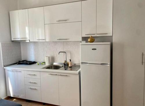 a white kitchen with a sink and a refrigerator at Livi beachfront Apartment in Durrës