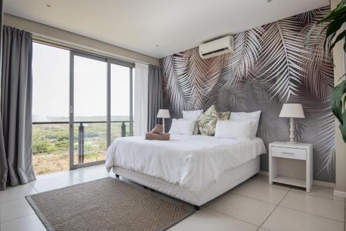 a bedroom with a large bed and a large window at 56 Zimbali Wedge in Ballito