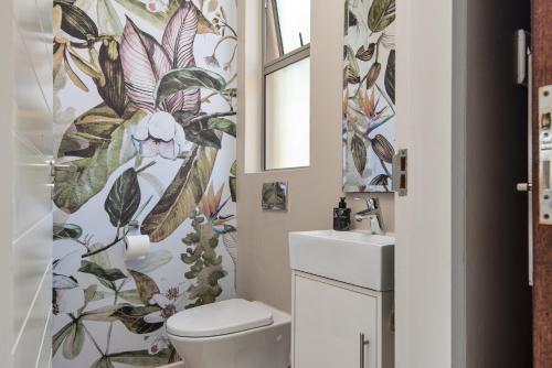 a bathroom with a toilet and a flower wallpaper at 56 Zimbali Wedge in Ballito