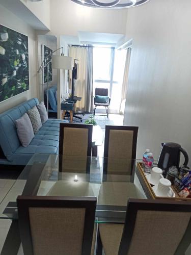uma sala de estar com um sofá azul e uma mesa em Cozy 1BR UPTOWN PARKSUITES Tower1 BGC em Manila