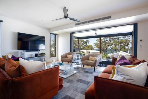 a living room with couches and a large window at Hyams Beach House A - Brand new lux beach Oasis in Hyams Beach