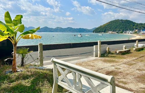 a white bench sitting next to a body of water at Beach Villa Tachibana in Onomichi