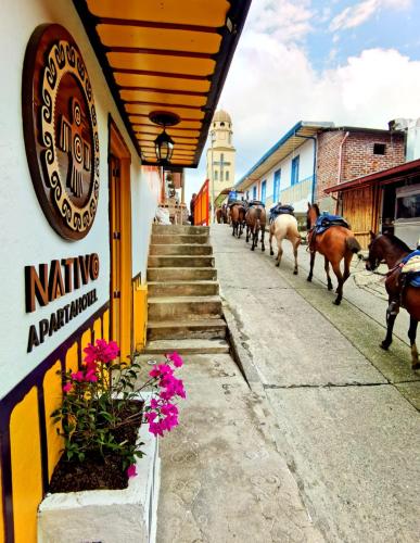a group of horses walking down a street with a building at Confortable Apartamento a 20 mt del Parque Principal in Salento