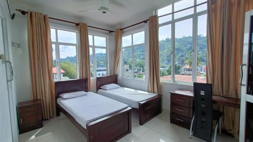 1 dormitorio con 2 camas y ventanas con vistas en Smile Hub Kandy Penthouse apartment en Kandy