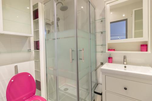 La salle de bains est pourvue d'une douche en verre et de toilettes roses. dans l'établissement VILLA LES PALMIERS, à Palavas-les-Flots