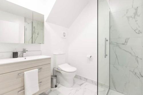 a white bathroom with a toilet and a glass shower at CBD with Style and Luxury - Free Parking in Christchurch