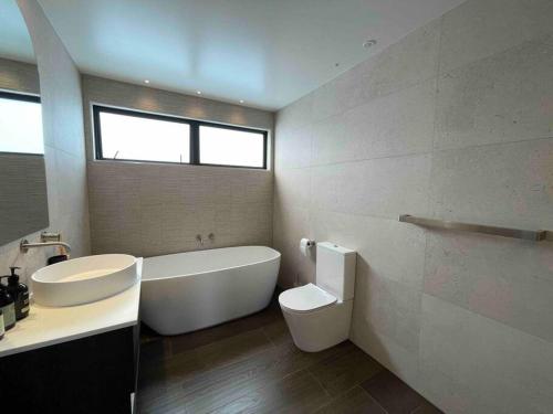 Luxury 3 Bedroom Home With Double Garage في كرايستشيرش: حمام مع حوض ومرحاض ومغسلة