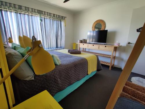 um quarto com uma cama, uma televisão e uma janela em Stylish Colourfull Getaway em Margaret River
