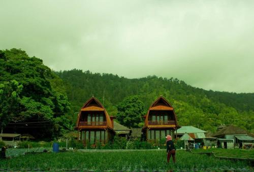 a person standing in front of two small houses at Villa Kedisan Lakeview in Kintamani