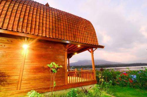 a wooden cabin with a deck in the grass at Villa Kedisan Lakeview in Kintamani