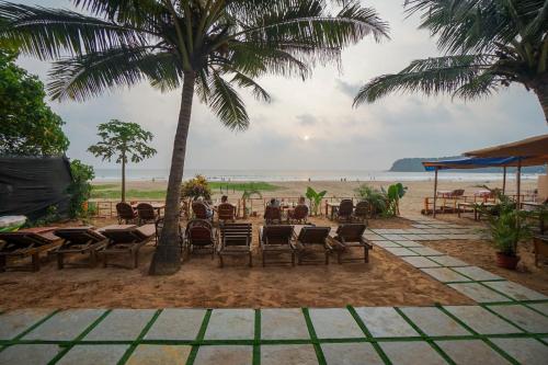 a table and chairs on a beach with palm trees at Sonho do Mar in Agonda