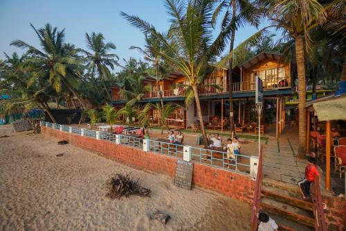 un complejo con palmeras y gente parada en la playa en Jardim a Mar en Agonda