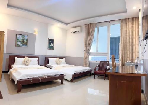 a bedroom with two beds and a table and a desk at Thanh Thu 1 Hotel in Kon Tum