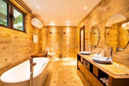 a bathroom with wooden walls and a tub and a sink at H Resort Bohol - The Coral Cliff by SMS Hospitality in Calape