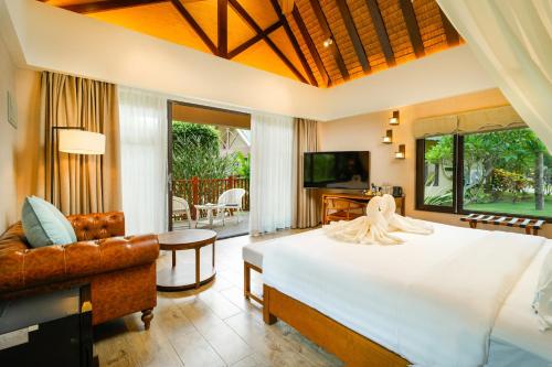 a bedroom with a bed and a couch and a television at H Resort - The Coral Cliff in Calape
