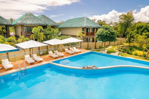 a pool at a resort with chairs and umbrellas at H Resort Bohol - The Coral Cliff by SMS Hospitality in Calape