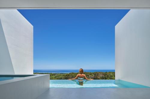 a man sitting in a infinity pool looking at the ocean at EMIL NAKIJIN in Shushi