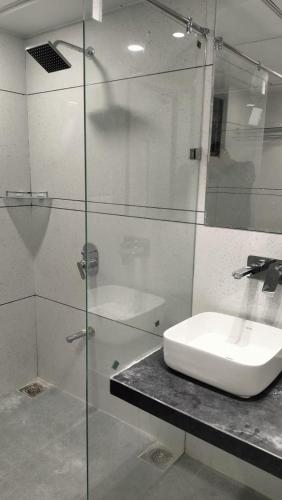 a bathroom with a glass shower and a sink at HOTEL AURELLIA in Sarkhej
