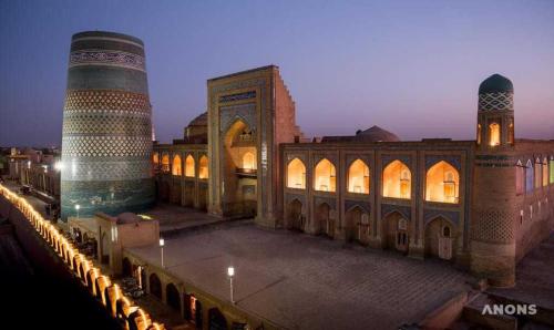 un bâtiment avec un minaret et une mosquée la nuit dans l'établissement Gavhar House, à Khiva