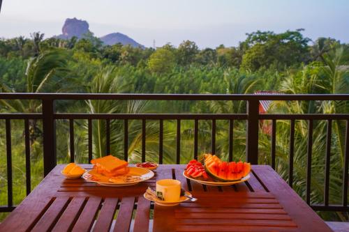 a wooden table with plates of fruit on a balcony at Sigiri Sierra View Resort in Sigiriya