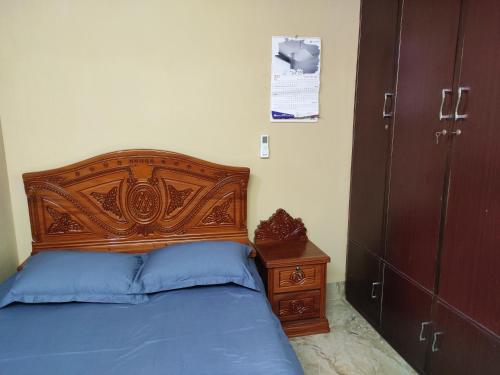 uma cama com uma cabeceira de madeira e uma mesa de cabeceira em Asma-ul-husna apartment em Rajshahi