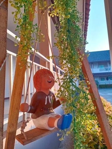 a doll sitting on a porch swing with plants at Chiangkham Grand Villa - SHA Certified in Chiang Kham