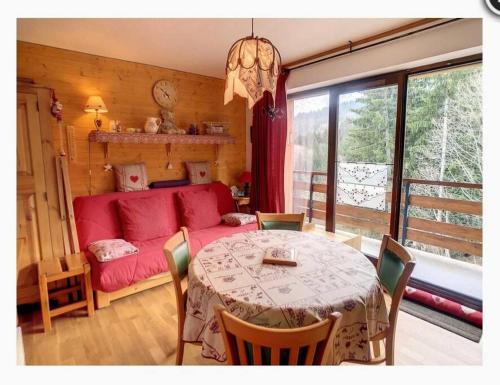 un salon avec une table et un canapé rouge dans l'établissement Appartement montagnard avec vue sur le Mont-Blanc, à Saint-Gervais-les-Bains