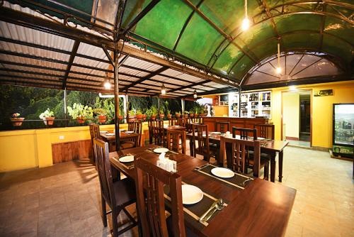 un ristorante con tavoli e sedie in legno e un soffitto verde di Hotel Odyssey Nepal a Kathmandu