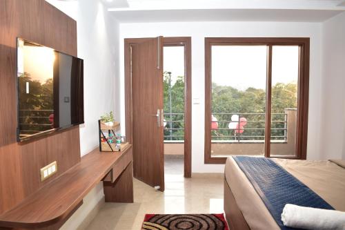 a bedroom with a bed and a television and a balcony at Qotel Hotel Ashok Vihar Couple Friendly in New Delhi