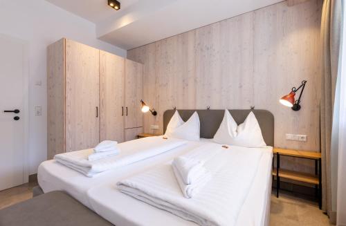 a bedroom with a large white bed with white pillows at wohn.genuss app traumhaus in Schladming