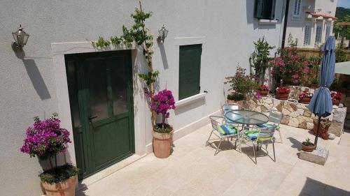a patio with a green door and a table and chairs at Apartments Villa Ina in Brseč