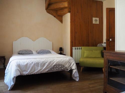- une chambre avec un lit et une chaise verte dans l'établissement Maison de La LAFONE, à Domme
