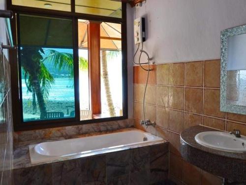 baño con bañera, lavabo y ventana en Family House, en Ko Por