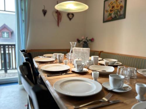 a long wooden table with plates and utensils on it at Traumhaft große Ferienwohnung nähe Attersee in Sankt Georgen im Attergau