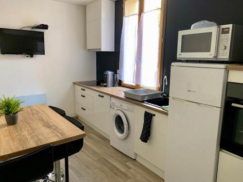 a kitchen with a washing machine and a microwave at Le passage de Hugues - 3 chambres - hyper centre in Troyes
