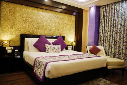 a bedroom with a large bed with purple pillows at The Vaishnavi in Deoghar