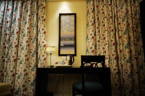 a desk with a chair in a room with curtains at The Vaishnavi in Deoghar