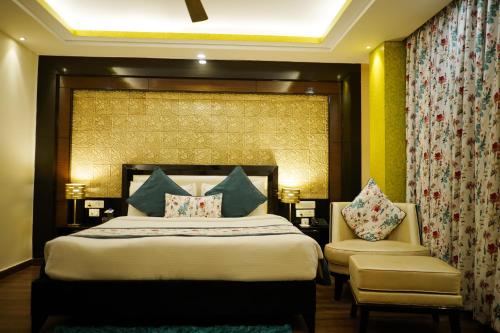 a bedroom with a large bed and a chair at The Vaishnavi in Deoghar