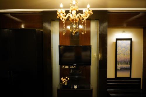 a living room with a television and a chandelier at The Vaishnavi in Deoghar