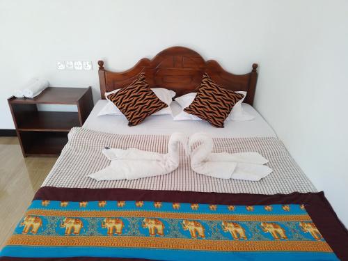 a bed with two pairs of socks and a bedspread at Nirwana Resort in Habarana
