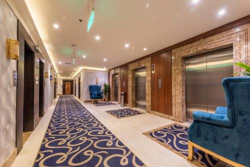 a hallway with a blue chair and a carpet at Paradise Inn Jeddah Hotel in Jeddah
